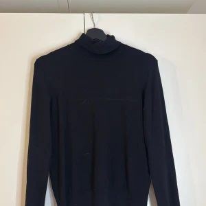 Svart polotröja - Snygg och stilren svart polotröja med långa ärmar. Perfekt för kyligare dagar och kan enkelt matchas med olika outfits. Ett måste i garderoben för en klassisk look. Köpt på H&M i höstas och använd få gånger 