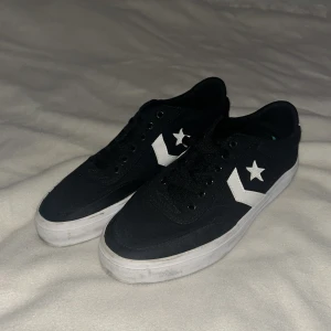 Svarta sneakers från Converse - Snygga svarta sneakers från Converse med vit sula och klassisk stjärndetalj på sidan. Skorna har snörning och en vit häl med Converse-logga. Perfekta för en avslappnad stil. Storlek 41 eur