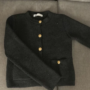 Svart stickad tröja  från Zara - Säljer en svart stickad tröja från Zara med guldknappar framtill. Endast använd ca 2 gånger och är i bra skick. Stl S.