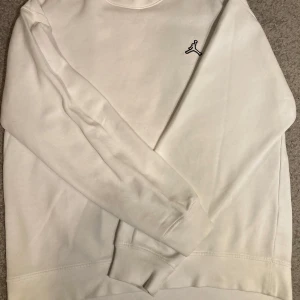 Vit tröja från Jordan - Säljer en stilren vit tröja från Jordan med det klassiska logotypen broderad på bröstet. Tröjan har långa ärmar och en bekväm passform, perfekt för en avslappnad stil. Tillverkad i mjukt material för extra komfort.