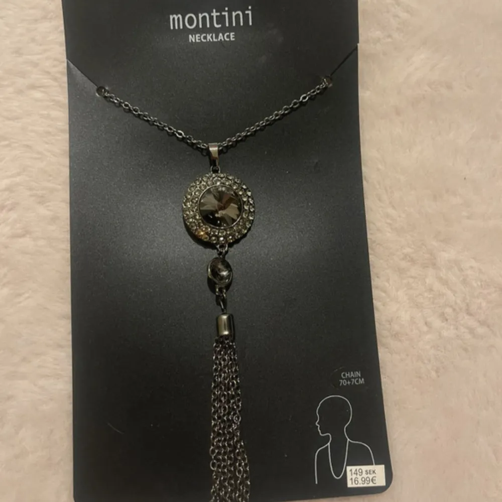 Elegant svart halsband från Montini med en glittrig cirkel och en hängande tofs. Kedjan är 70-76 cm lång och har en stilren design som passar perfekt till olika tillfällen.. Asusteet.