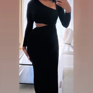 Svart oneshoulder klänning från Asos - Snygg svart oneshoulder klänning med lång ärm och en stilren cut-out detalj i midjan. 