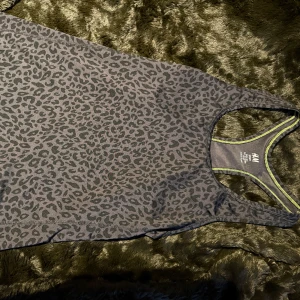 Grå leopardmönstrad linnetopp från H&M - Snygg grå linnetopp från H&M med leopardmönster. Toppen har en sportig design med brottarrygg och kontrasterande sömmar i neongult.