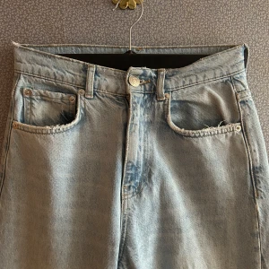 Ljusa jeans med slitningar - Snygga ljusa jeans med slitningar på knäna. De har en klassisk femficksdesign och en knappgylf. Perfekta för en avslappnad stil.