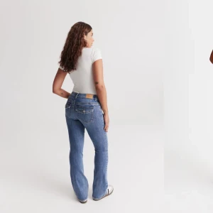 Blå bootcut jeans - Snygga blå bootcut jeans med låg midja och klassisk femficksdesign. Perfekta för en avslappnad stil med en vit t-shirt och sneakers.