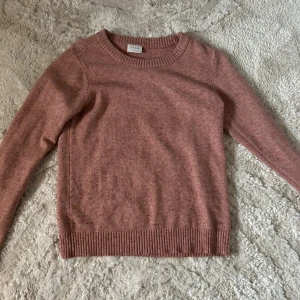 Rosa stickad tröja från Vila - Mysig rosa stickad tröja från Vila med rund halsringning och ribbade kanter. Perfekt för kyligare dagar och ger en stilren look. Passar bra till både jeans och kjol.