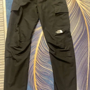 Svarta byxor från The North Face - Säljer ett par svarta byxor från The North Face med praktiska fickor på sidorna. Perfekta för utomhusaktiviteter och har en stilren design med logotypen på benet. Den är knappt använd och säljer för att jag inte använder den. Pris går att diskutera. Det går att frackta och kan mötas i Stockholm exakt tid och plats diskuteras privat.