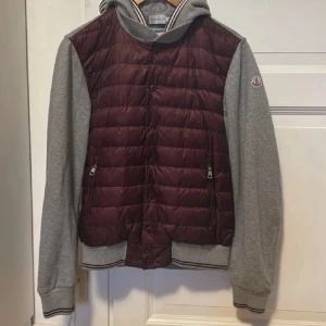 Moncler Cardigan  - Säljer en snygg vinröd och grå cardigan från Moncler. Jackan är i storlek M, men skulle säga att den passar mindre. Fråga gärna vid funderingar, OBS priset är inte hugget i sten.