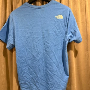 Blå t-shirt och blåa shorts från The North Face - Säljer en blå t-shirt och blåa shorts från The North Face med tryck på bröstet och ryggen. Perfekt för en avslappnad stil. T-shiten är M och shortsen L