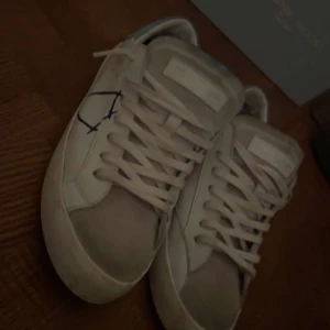 Philippe Model - Snygga vita sneakers från Philippe Model med blå detaljer. Skorna har en klassisk snörning och en stilren design. Perfekta för en avslappnad stil. De är gjorda med slitningar och det kommer med skorna. Cond 9/10 använda vid 5 tillfällen. Först till kvarn, pris är hugget i sten. Tar imot byten. Ställ gärna frågor tex mer bilder eller tydligare bilder. Vänliga hälsningar Barkarbycloset 🍾