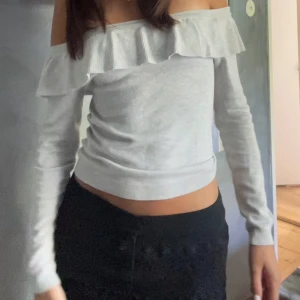 Vit offshoulder topp - Säljer en stilren vit offshoulder topp med volangdetalj. Toppen är långärmad och har en tight passform, perfekt för både vardag och festliga tillfällen.