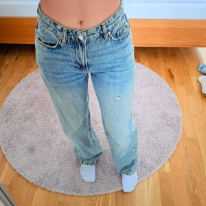 Blå "Perfect Jeans" 34 från Gina Tricot - Blå jeans med en straight fit. De har en hög midja och medvetet slitage på högre byxben. Använd 1-3 gånger. 🩵