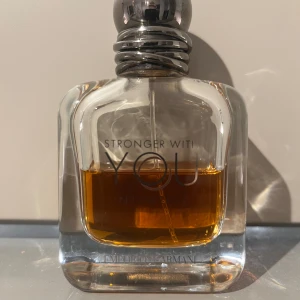 Stronger With You Intensely från Emporio Armani - Säljer en flaska av parfymen Stronger With You Intensely från Emporio Armani. Flaskan har en elegant design med en mörk bärnstensfärgad vätska och en stilren metallkork. Perfekt för den som vill ha en intensiv och långvarig doft.