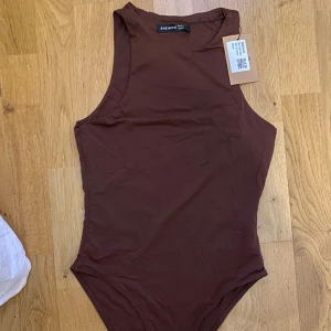 Brun body från Shein - brun body från Shein med hög hals och ärmlös design köpt från sellpy i kategorin ”mycket bra skick”. Materialet känns mjukt och bekvämt mot huden.