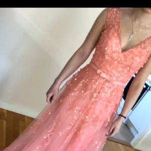 Rosa festklänning - Säljer en fantastisk rosa långklänning med paljetter. Klänningen har en v-ringad design och är ärmlös, vilket ger en elegant look. Perfekt för fester. 