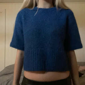 Trekvarsärmad tröja - Säljer en snygg blå stickad tröja med trekvartsärmade ärmar från Zara. Tröjan är croppad och har en ribbad kant nedtill. Perfekt för en stilren look.