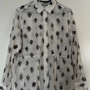 Silkeblus, & other stories, 42, svart/vit - Blus i silke från & other stories i storlek 42, svart/vit. Snäckmotiv. I mycket fint skick. 70% bomull, 30% silke. Kan dras åt i midjan. Stängs med små diskreta knappar fram. 