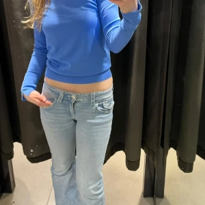 Ljusblå bootcut jeans - Säljer ett par ljusblå bootcut jeans från Gina tricot med klassisk femficksdesign. Jeansen har en lågmidjad passform och är perfekta för en avslappnad stil. Jeansen är från barnavdelningen i storlek 158cm från Gina tricot men passar storlek 34-36 i petite.