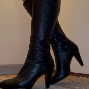 Svarta stövlar med klack - Otroligt sexiga svarta stövlar i skinn med klack och spetsig tå. Perfekta för en elegant look. De har en stilren design som passar till många olika outfits. Jag älskar dessa men har alldeles för många så måste göra mig av med dom😭dom är från tamaris i strl 37 o sitter som en smäck runt vaderna. Har satt på glid skydd under skon för att man nt ska halka o dö. Så stor kärlek för dessa hoppas att någon annan kan uppskatta dom som jag
