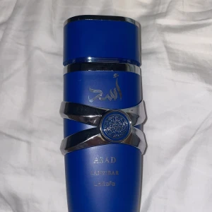 Asad Zanzibar Eau de Parfum från Lattafa - 95-97 ml. Jätte lite använt. Säljer en elegant Asad Zanzibar Eau de Parfum från Lattafa. Flaskan är djupblå med silverdetaljer och har en unik design med ett dekorativt emblem. Perfekt för den som söker en sofistikerad doftupplevelse. Den håller lukten i 6-8 timmar och kan hålla längre om man lägger vaseline. Man får många komplimanger med det. 