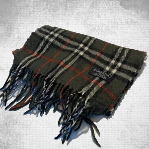 Grön Burbuerry scarf - STEAL! Säljer denna hög kvalitets scarfen från Burberry. Skick 9/10 Färgen är mörk grön. Hör av dig vid frågor!