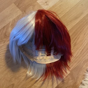 Röd och vit peruk todoroki - Snygg peruk med tvåfärgad design i rött och vitt. Perfekt för cosplay eller temafester. Den har en kort och stilren frisyr som ger en cool look. Todoroki från mha 