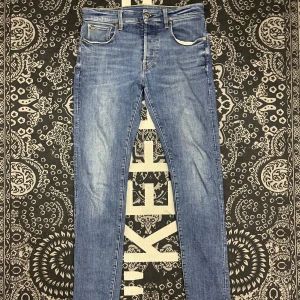 Blå jeans från G-Star RAW - Snygga blå jeans från G-Star RAW med en slim passform. De har klassiska fem fickor och en läderdetalj med logotyp på baksidan. Perfekta för en stilren look.