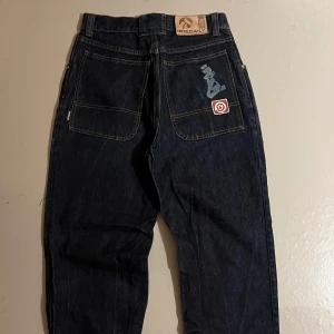 Mörkblå jeans från Irie Daily - Snygga mörkblå jeans från Irie Daily med unika tryckdetaljer på bakfickan. Jeansen har en klassisk femficksdesign och en bekväm passform. Perfekta för en avslappnad stil.