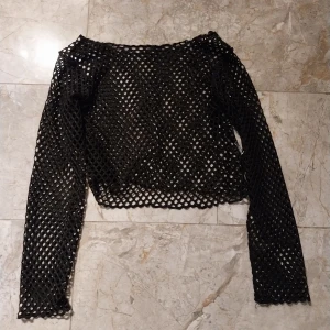 Svart nättröja - Snygg svart nättröja med långärmad design. Perfekt för att lägga över en annan topp för en cool lager-på-lager-look. Finns ingen lapp med storlek tyvärr, ganska liten. Säljes pga att den inte används längre. Katt finns I hemmet. 