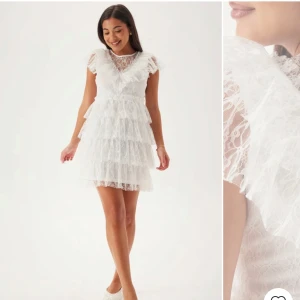 Vit spetsklänning med volanger - Charmig vit spetsklänning med volanger och v-ringad design. Klänningen har korta ärmar och en elegant knäppning i ryggen. Perfekt för studenten! Ordinarie pris 899kr. Aldrig använd,endast provad!
