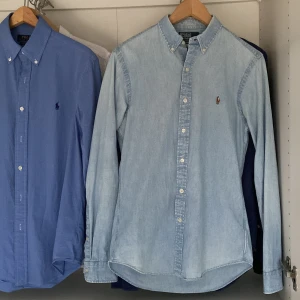 Ljusblå skjorta från Ralph Lauren - Snygg ljusblå skjorta från Ralph Lauren i slim fit. Skjortan har långa ärmar och klassiska knappar framtill. Perfekt för en stilren look med den ikoniska broderade loggan på bröstet.