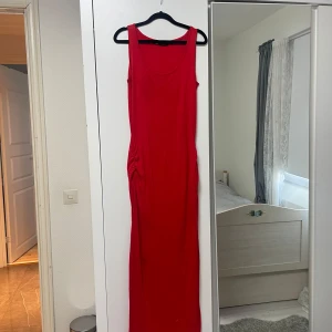 Röd ärmlös långklänning - Snygg röd långklänning i ett mjukt och bekvämt material. Perfekt för sommarens alla fester eller en avslappnad dag på stan. Den är ärmlös och har en figurnära passform som framhäver silhuetten. Ett måste i garderoben för den som älskar stilrena plagg!