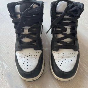 Air Jordan 1 Mid - Air Jordan i svart/vitt med mörkgröna spräckliga detaljer. Inköpta på Footlocker MOS vintern 2023.