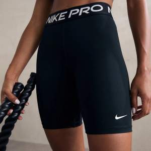 Säljer ett par svarta Nike Pro träningsshorts i mycket bra skick. De är högmidjade och har en tight passform, perfekt för gymmet eller löprundan. Materialet är stretchigt och bekvämt, med en elastisk midja för extra stöd. Nike-loggan syns på benet och midjebandet.