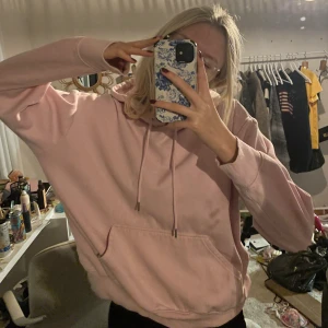 Rosa hoodie - Mysig rosa hoodie i oversized passform. Perfekt för chill dagar eller när du vill ha något bekvämt och stilrent. Den har en klassisk känguruficka och justerbar huva med snören. Passar perfekt till jeans eller leggings!