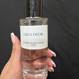 Gris Dior parfym - Säljer en elegant Gris Dior parfym från Christian Dior. Flaskan är stilren och genomskinlig med en svart kork och vit etikett. Perfekt för den som älskar lyxiga dofter. Flaskan är nästan full, så det finns mycket kvar att njuta av. Passa på att köpa denna exklusiva doft!