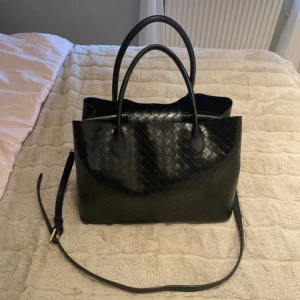 svart skolväska - Stor svart väska som är perfekt till skolan. Fick den förra julen men den kommer tyvär inte till användning så därav säljer jag den. Ser nästan helt oanvänd ut, superbra skick! Fejk skinn med ett flätat mönster. Nypris är 599kr men jag säljer den i superbra skick för 399kr! Den har ett fack för datorn i mitten med dragkedja och sen finns även tvả mindre fack (syns på bilderna) Finns även ett längre axelband som man kan ta av. hör bara av dig om du har frågor! <3