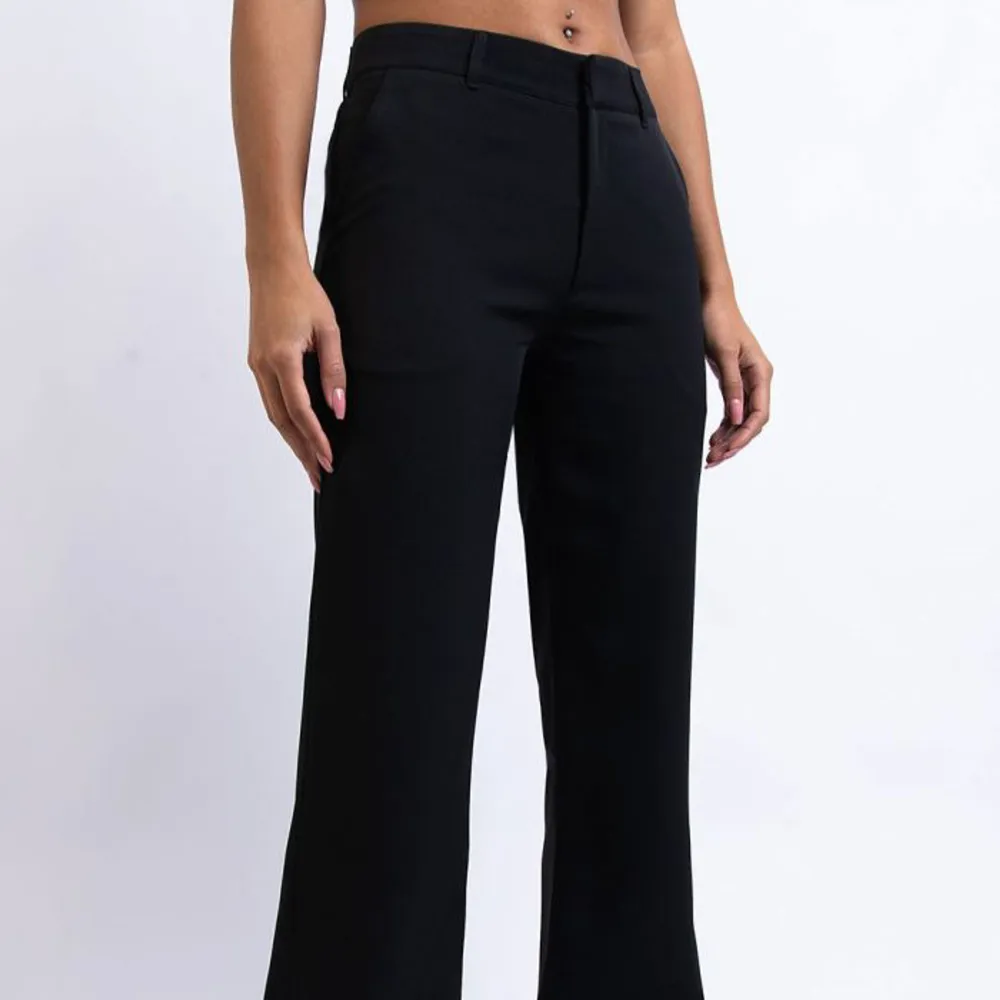 Snygga svarta kostymbyxor i mid waist modell. Perfekta för både kontoret och festliga tillfällen. De har en klassisk straight passform och är tillverkade i ett bekvämt material som ger en stilren look.. Farkut & Housut.