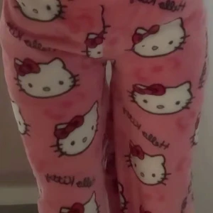 Rosa Hello Kitty mjukisbyxor - Supermysiga rosa mjukisbyxor med Hello Kitty-motiv över hela tyget. Perfekta för en chill dag hemma eller som en söt pyjamasbyxa. De är gjorda i ett mjukt material som känns skönt mot huden. Byxorna har en lös passform för extra komfort.
