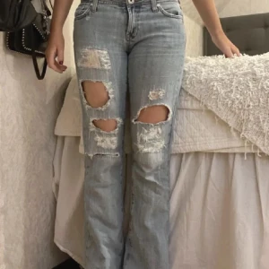 lågmidjade bootcut jeans - Säljer ett par ljusa jeans med coola slitningar på låren och knäna. Köpte de här på plick men har knappt använda de då de inte satt som jag hoppades på!🩷
