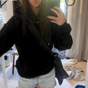 Svart hoodie - Säljer en svart hoodie i mycket bra skick. Den är perfekt för höst och vinter med sin mysiga och varma känsla. Hoodien har en klassisk design med en stor ficka fram och justerbar huva med snören. Passformen är normal och den är gjord av mjukt material som känns skönt mot huden.
