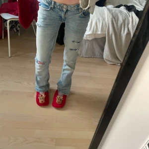 Ljusblå jeans med slitningar - Säljer ett par ljusblå jeans i bra skick. De har slitningar ”hål” på sig och det är liksom designen. Säljer då de sällan kommer till användning. Low waist, boot cut. Värda typ  600 därmed högt pris. 