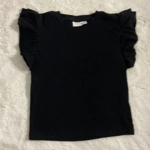 Svart topp med volanger - Knappt använd ser ut som ny