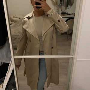 Beige trenchcoat  - Helt ny oanvänd trenchcoat med lapparna kvar. Köptes för 1600kr, jättebra kvalitet. Kan skicka fler bilder