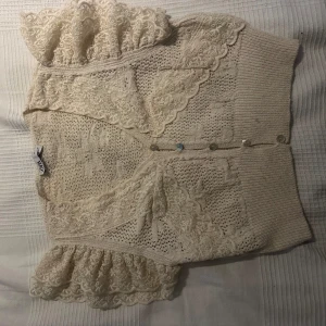 Beige kofta med spetsdetaljer - Säljer en superfin beige kofta från Zara med vackra spetsdetaljer. Den har korta ärmar med volang och knappar framtill. Perfekt för vår och sommar när du vill ha något lätt och stiligt. Passar både till vardags och fest!