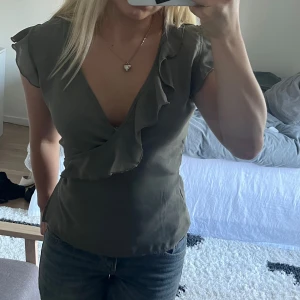 Topp  - Beige- grå topp, har en fläck där nere på tröjan som bara syns i vissa ljus , går inte att få med på bild , kanske går att få bort,, toppen går att knyta på olika sätr 