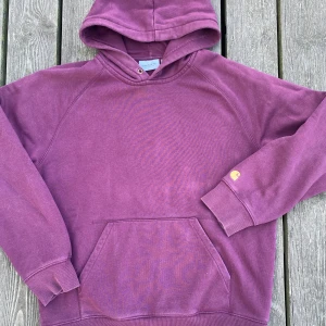 Carhatt hoody - Vinröd hoody från Carhartt. Använd men i bra skicka. Tjock, hög kvalitét sweatshirt. Storlek M Bild tagen i stark solljus, hoodyn är inte alls så solblekt som den ser ut. 