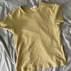 Gul t-shirt - Säljer en enkel och stilren gul t-shirt. Perfekt för vardagsbruk med sin mjuka bomullskänsla och korta ärmar. Passar bra till både jeans och shorts för en avslappnad look.