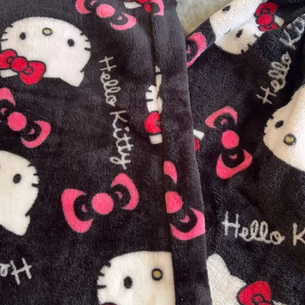 Supermysiga Hello Kitty mjukisbyxor i svart med ett gulligt mönster av Hello Kittys ansikte och rosa rosetter. Perfekta för att chilla hemma eller ha en avslappnad dag. De är gjorda i ett mjukt och skönt material som känns härligt mot huden. (de vita på sista bilden finns i en annan annons)🩷. Jeans & Byxor.