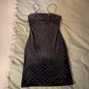 Svart klänning med prickar - Säljer en super fin svart klänning med glitter på hela. Den är ärmlös med smala axelband och har en tight passform. Perfekt för festliga tillfällen eller andra val.💗                                                                   ((säljer pga den int blir använd))